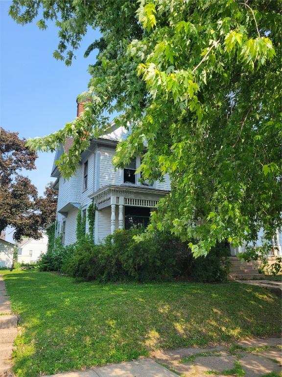 606 Meridian St, Tipton, IA 52772 - view of side of property featuring a chimney and a lawn
