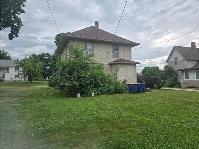 708 E 4th St, Vinton, IA 52349 - view of home's exterior featuring a lawn and a chimney
