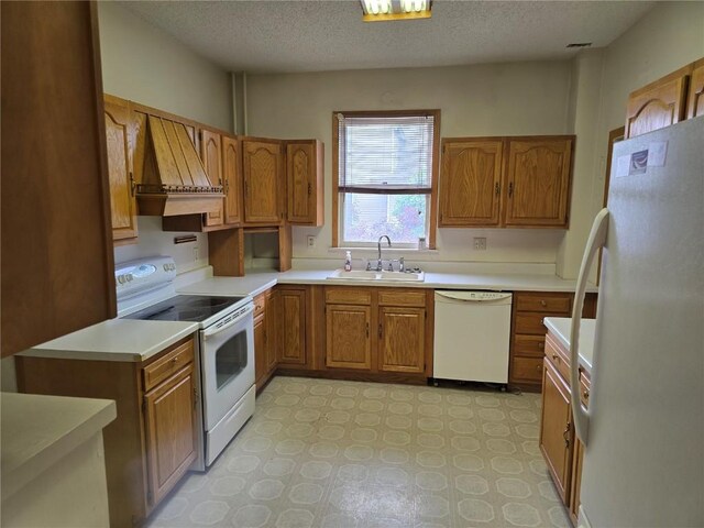 708 E 4th St, Vinton, IA 52349 - kitchen featuring white appliances, custom range hood, brown cabinets, light countertops, and a textured ceiling