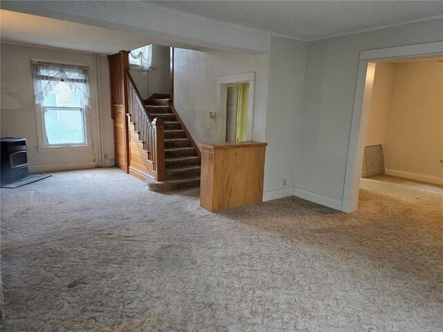 708 E 4th St, Vinton, IA 52349 - unfurnished living room with a wood stove, stairs, carpet, and crown molding