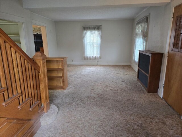 708 E 4th St, Vinton, IA 52349 - unfurnished living room featuring carpet floors, stairway, and crown molding