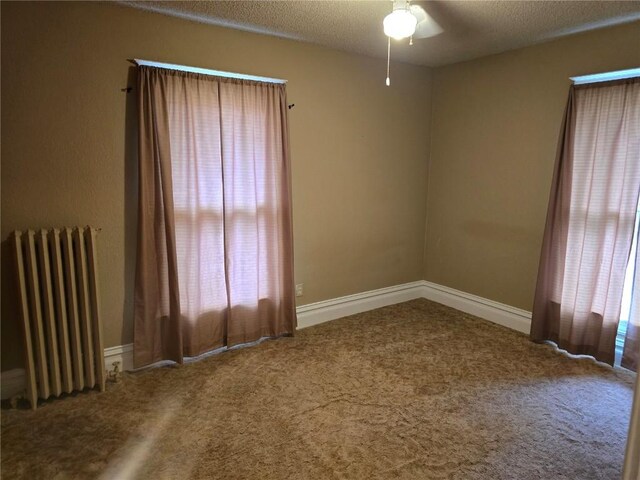 708 E 4th St, Vinton, IA 52349 - carpeted empty room featuring radiator heating unit, ceiling fan, and a textured ceiling