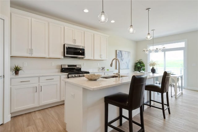1417 Echo Ridge Ln, Marion, IA 52302 - kitchen featuring stainless steel appliances, light wood-style floors, a kitchen island with sink, a kitchen bar, and white cabinets