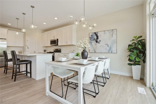 1417 Echo Ridge Ln, Marion, IA 52302 - kitchen featuring appliances with stainless steel finishes, a center island with sink, a breakfast bar, light wood finished floors, and light countertops