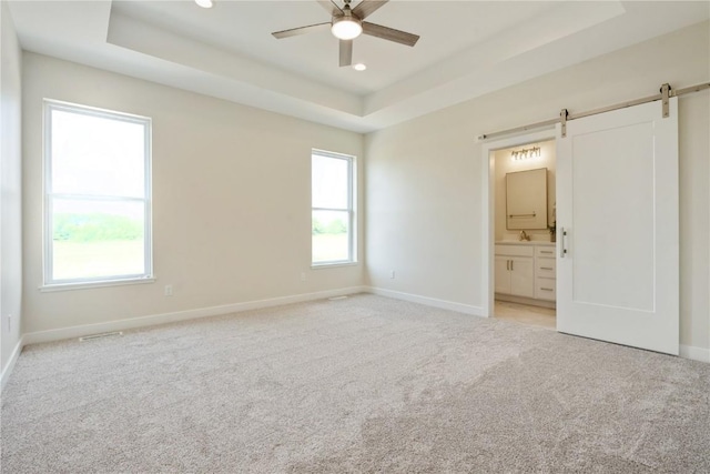 1417 Echo Ridge Ln, Marion, IA 52302 - unfurnished bedroom featuring a tray ceiling, a barn door, light carpet, connected bathroom, and recessed lighting