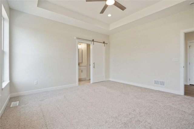 1417 Echo Ridge Ln, Marion, IA 52302 - unfurnished bedroom featuring a barn door, light colored carpet, a raised ceiling, recessed lighting, and connected bathroom