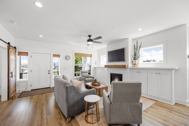 1153 Cedar Springs Dr, Marion, IA 52302 - living room with light wood finished floors, a ceiling fan, a brick fireplace, recessed lighting, and a barn door