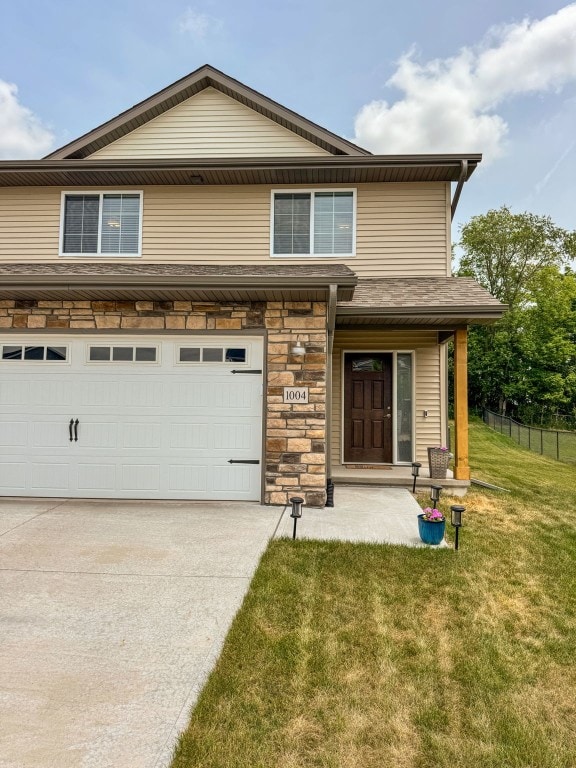 1004 Creekside Dr, Tiffin, IA 52340 - view of front facade with a front lawn, stone siding, concrete driveway, and a garage