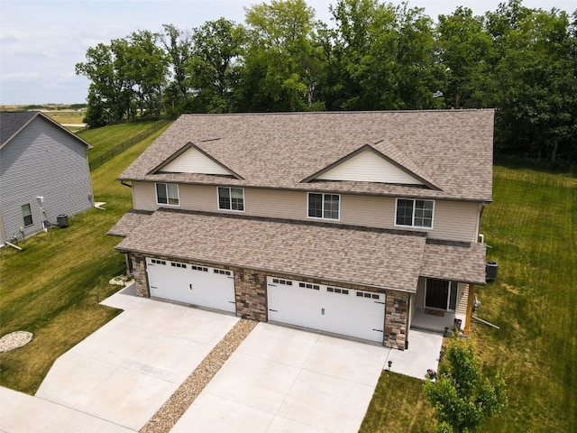 1004 Creekside Dr, Tiffin, IA 52340 - view of front facade with concrete driveway, stone siding, a shingled roof, an attached garage, and a front lawn