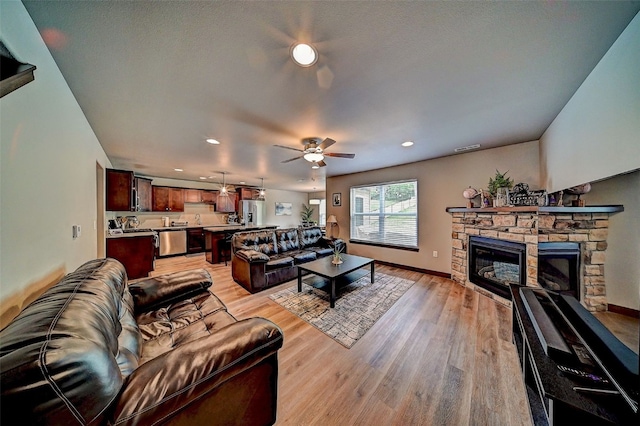 1004 Creekside Dr, Tiffin, IA 52340 - living room featuring a stone fireplace, recessed lighting, ceiling fan, and light wood finished floors