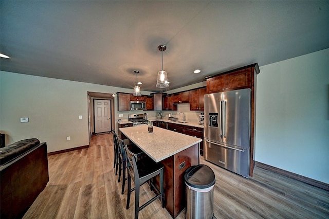 1004 Creekside Dr, Tiffin, IA 52340 - kitchen featuring appliances with stainless steel finishes, light wood-style flooring, a kitchen island, pendant lighting, and a kitchen breakfast bar