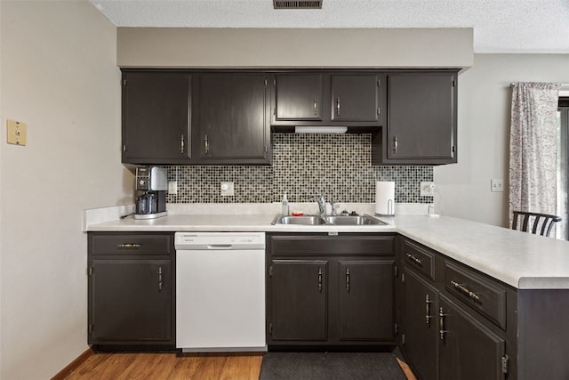 4485 Armar Dr SE Unit 101, Cedar Rapids, IA 52403 - kitchen with white dishwasher, a peninsula, light countertops, wood finished floors, and tasteful backsplash