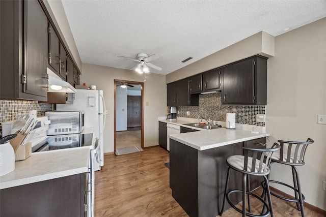 4485 Armar Dr SE Unit 101, Cedar Rapids, IA 52403 - kitchen with a ceiling fan, under cabinet range hood, backsplash, a peninsula, and a breakfast bar