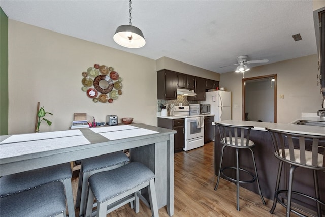 4485 Armar Dr SE Unit 101, Cedar Rapids, IA 52403 - kitchen with white appliances, under cabinet range hood, light wood-style flooring, light countertops, and a kitchen breakfast bar