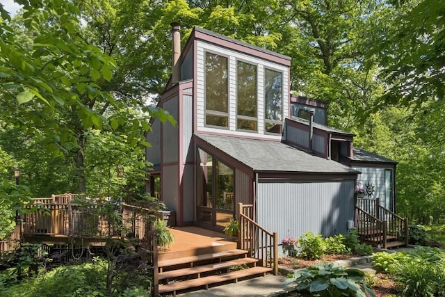 2520 NE Sugar Bottom Rd, Solon, IA 52333 - view of front of house featuring a wooden deck, roof with shingles, view of wooded area, and a chimney