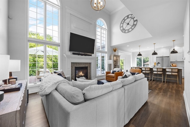 1574 Turkey Ridge Ct NW, Swisher, IA 52338 - living area featuring a high ceiling, crown molding, healthy amount of natural light, a glass covered fireplace, and dark wood-style floors