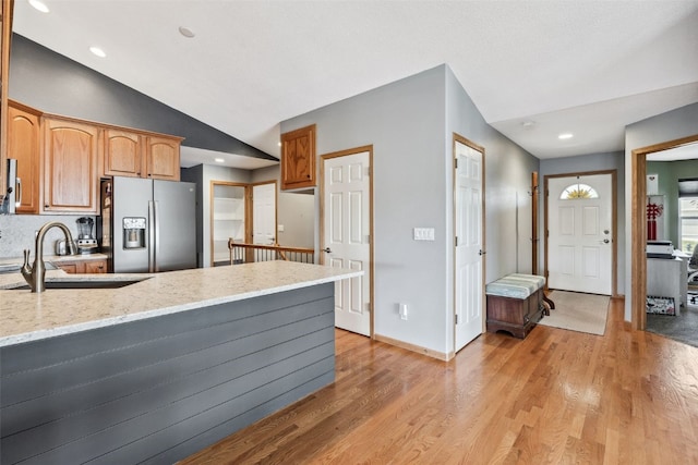 4131 Lakeview Dr SW, Cedar Rapids, IA 52404 - kitchen with stainless steel refrigerator with ice dispenser, vaulted ceiling, a peninsula, light wood-style flooring, and light stone countertops