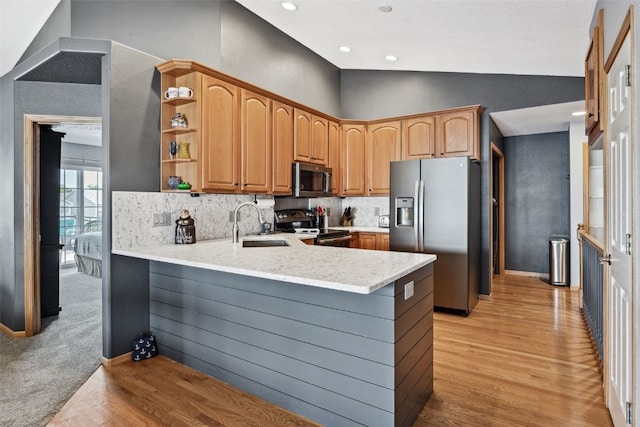 4131 Lakeview Dr SW, Cedar Rapids, IA 52404 - kitchen with appliances with stainless steel finishes, a peninsula, light wood finished floors, lofted ceiling, and backsplash