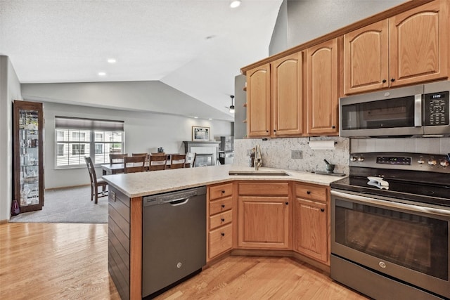 4131 Lakeview Dr SW, Cedar Rapids, IA 52404 - kitchen featuring appliances with stainless steel finishes, vaulted ceiling, a peninsula, light wood-style flooring, and decorative backsplash