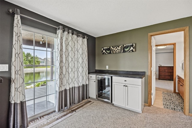 4131 Lakeview Dr SW, Cedar Rapids, IA 52404 - indoor dry bar featuring beverage cooler, light carpet, a water view, and a textured ceiling