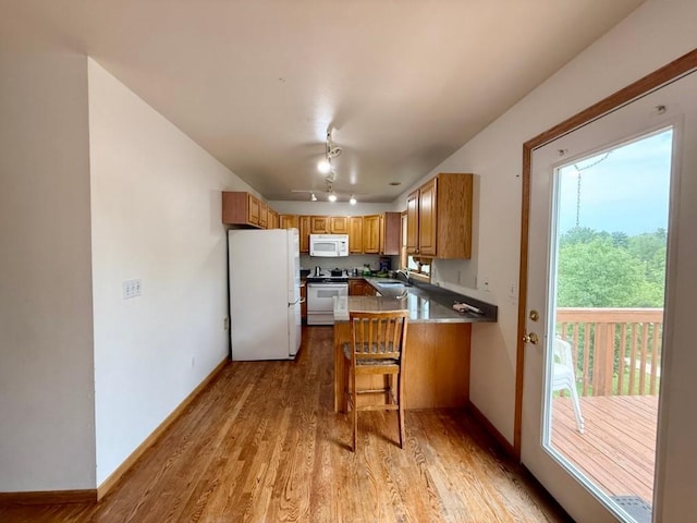 2208 Holiday Rd, Coralville, IA 52241 - kitchen with white appliances, light wood-style floors, a peninsula, brown cabinets, and track lighting