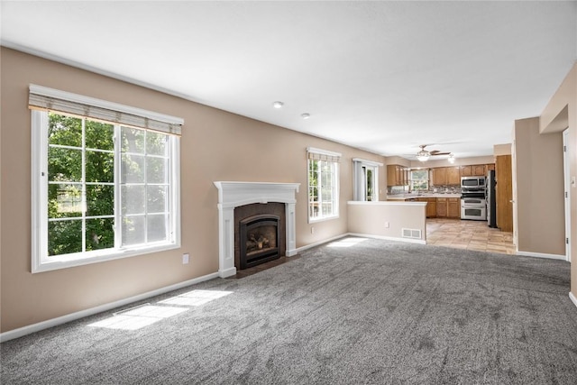 4127 Harwood Dr NE, Cedar Rapids, IA 52411 - unfurnished living room with light colored carpet, a fireplace with flush hearth, and a ceiling fan