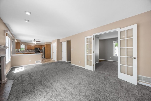 4127 Harwood Dr NE, Cedar Rapids, IA 52411 - unfurnished living room with french doors, ceiling fan, light carpet, and a fireplace with flush hearth