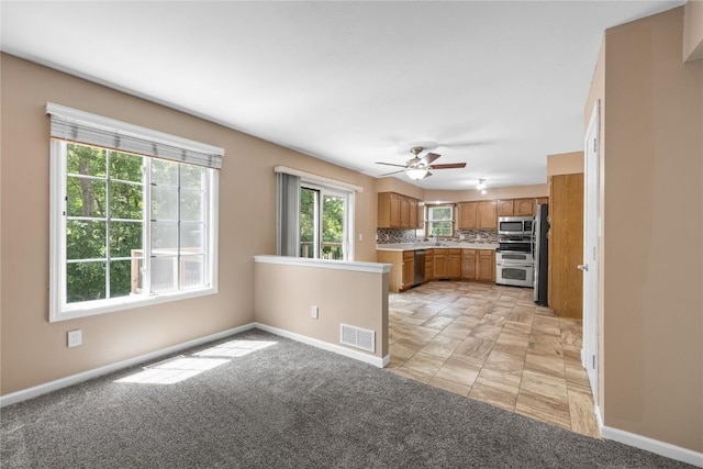 4127 Harwood Dr NE, Cedar Rapids, IA 52411 - kitchen with stainless steel appliances, light countertops, backsplash, ceiling fan, and brown cabinets