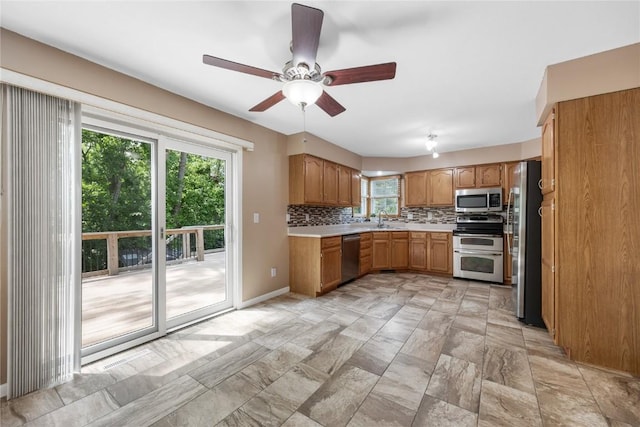 4127 Harwood Dr NE, Cedar Rapids, IA 52411 - kitchen with stainless steel appliances, light countertops, backsplash, ceiling fan, and brown cabinetry