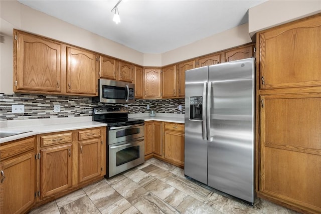 4127 Harwood Dr NE, Cedar Rapids, IA 52411 - kitchen featuring appliances with stainless steel finishes, brown cabinetry, light countertops, and tasteful backsplash