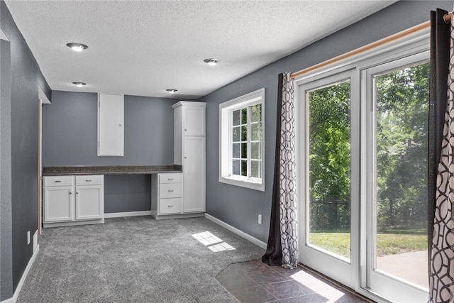 4127 Harwood Dr NE, Cedar Rapids, IA 52411 - kitchen featuring carpet floors, a textured ceiling, white cabinetry, dark countertops, and built in study area