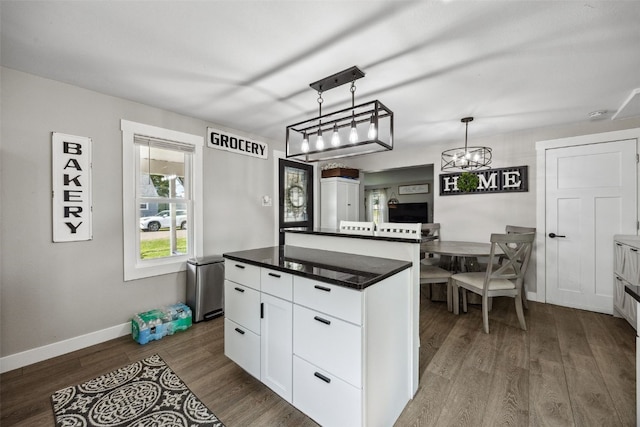 518 Main St, Fairfax, IA 52228 - kitchen with dark wood finished floors, dark countertops, white cabinets, a chandelier, and hanging light fixtures