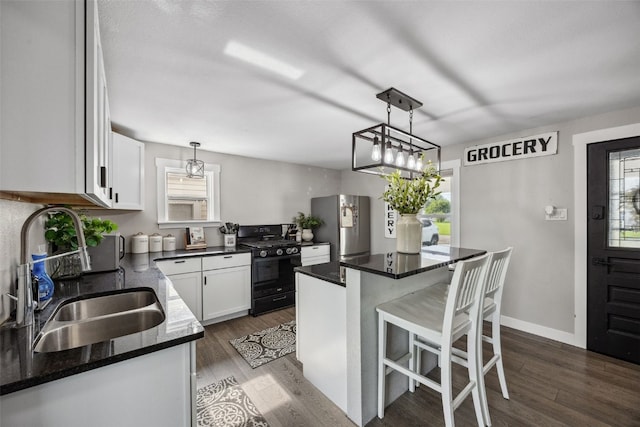 518 Main St, Fairfax, IA 52228 - kitchen with freestanding refrigerator, black range with gas cooktop, white cabinets, and dark wood finished floors