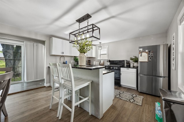 518 Main St, Fairfax, IA 52228 - kitchen featuring freestanding refrigerator, black gas range oven, dark countertops, and white cabinets