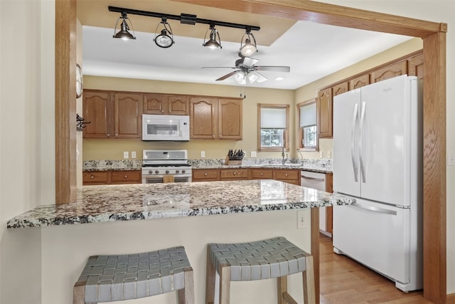 1865 Rock Island Dr, Ely, IA 52227 - kitchen featuring white appliances, a peninsula, light stone countertops, a ceiling fan, and light wood-type flooring