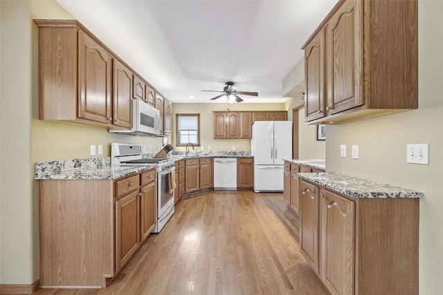 1865 Rock Island Dr, Ely, IA 52227 - kitchen featuring white appliances, light wood-style flooring, ceiling fan, light stone countertops, and brown cabinetry