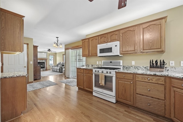 1865 Rock Island Dr, Ely, IA 52227 - kitchen featuring white appliances, a ceiling fan, light wood-style floors, a chandelier, and light stone countertops