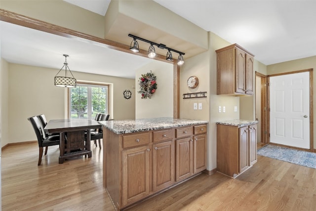 1865 Rock Island Dr, Ely, IA 52227 - kitchen featuring light wood-type flooring, rail lighting, brown cabinets, light stone counters, and hanging light fixtures