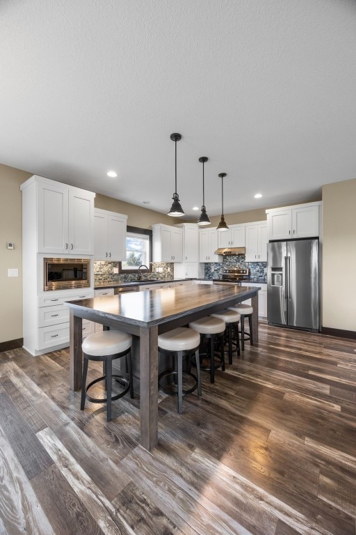 3363 Southridge Dr, Amana, IA 52203 - kitchen with appliances with stainless steel finishes, dark countertops, a center island, decorative backsplash, and white cabinets