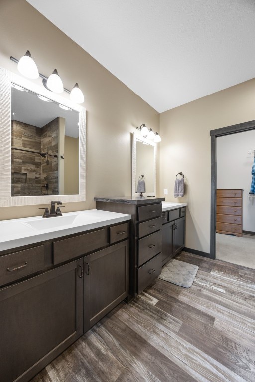 3363 Southridge Dr, Amana, IA 52203 - bathroom featuring wood finished floors, two vanities, and tiled shower