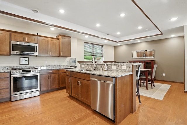 1102 S St, Urbana, IA 52345 - kitchen with appliances with stainless steel finishes, a kitchen breakfast bar, light wood-style floors, a kitchen island with sink, and recessed lighting