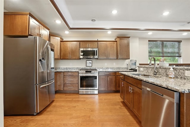 1102 S St, Urbana, IA 52345 - kitchen featuring stainless steel appliances, light wood-type flooring, light stone counters, brown cabinetry, and recessed lighting