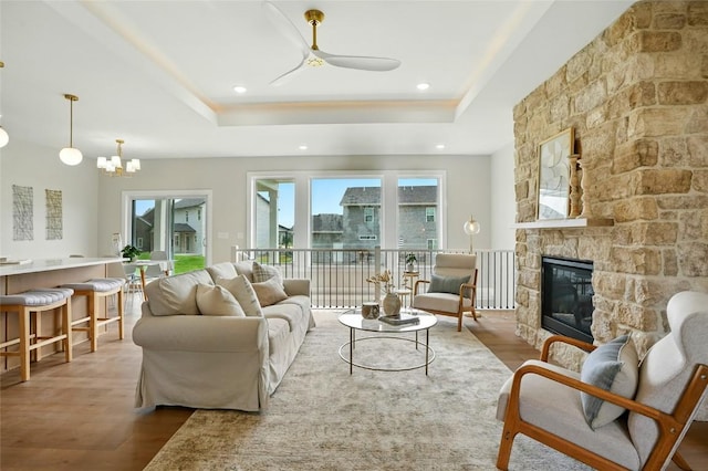 1002 Croell Ave, Tiffin, IA 52340 - living room featuring wood finished floors, a raised ceiling, a ceiling fan, a chandelier, and a fireplace