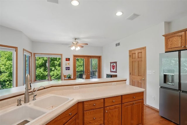 4317 Indian Tl NE, Solon, IA 52333 - kitchen with stainless steel fridge, light countertops, light wood-style flooring, ceiling fan, and brown cabinets