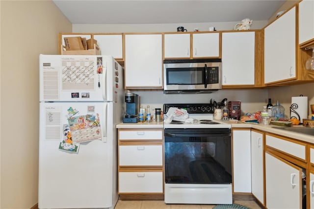 1230 Murray NE Unit 10, Cedar Rapids, IA 52402 - kitchen featuring freestanding refrigerator, stainless steel microwave, range with electric stovetop, light countertops, and white cabinets
