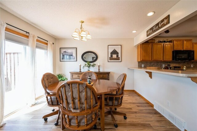 4593 Spoonbill Ct, Marion, IA 52302 - dining area with a chandelier, light wood-style flooring, recessed lighting, and a textured ceiling