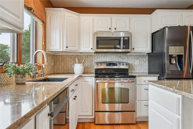 5515 W Mustang Rd NE, Cedar Rapids, IA 52411 - kitchen featuring stainless steel appliances, white cabinetry, decorative backsplash, light stone countertops, and light wood-style flooring