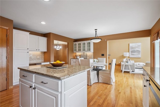 5515 W Mustang Rd NE, Cedar Rapids, IA 52411 - kitchen featuring tasteful backsplash, light wood-type flooring, a kitchen island, white cabinetry, and hanging light fixtures