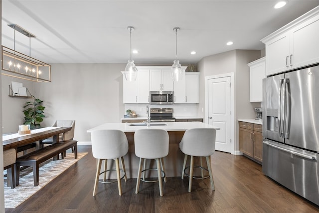 1953 Bowstring Dr, Marion, IA 52302 - kitchen with stainless steel appliances, light countertops, a breakfast bar, an island with sink, and dark wood-style flooring