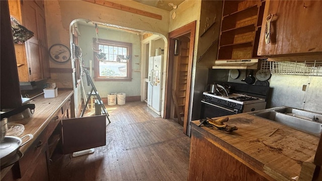 419 21st St NE, Cedar Rapids, IA 52402 - kitchen featuring white gas stove, dark wood-type flooring, under cabinet range hood, arched walkways, and brown cabinetry